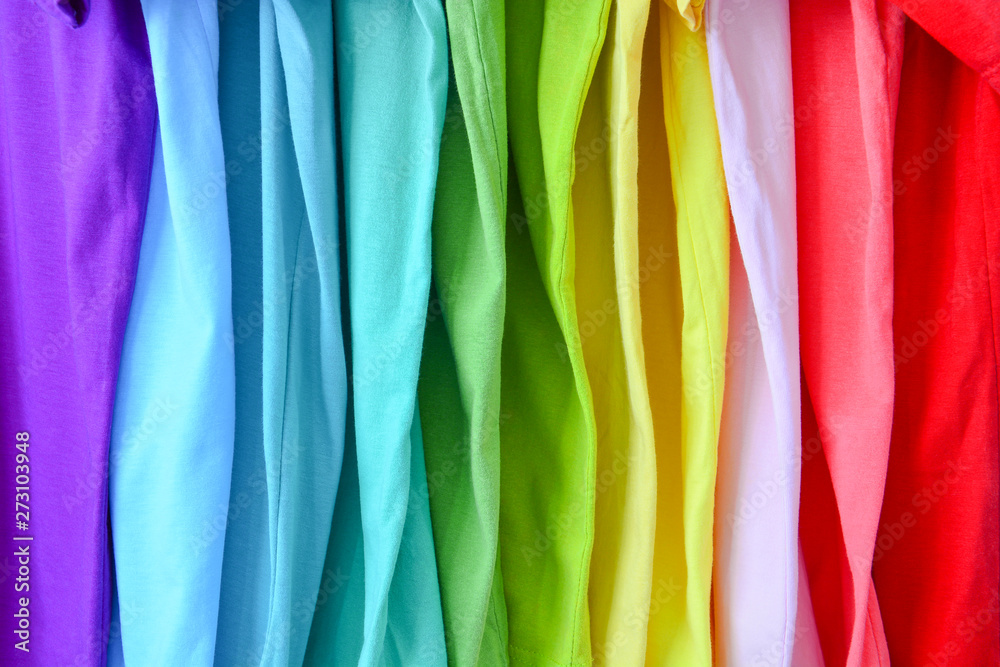 close up collection of colorful rainbow t-shirts hanging on clothes hanger in closet for texture background
