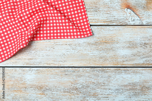 Checkered picnic blanket on wooden background, top view. Space for text