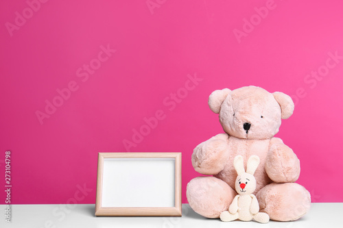 Photo frame and adorable toys on table against color background, space for text. Child room elements