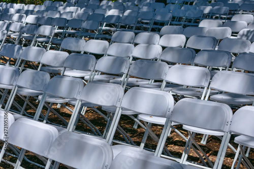 White plastic chairs set up an outdoor in row before ceremony, event or party