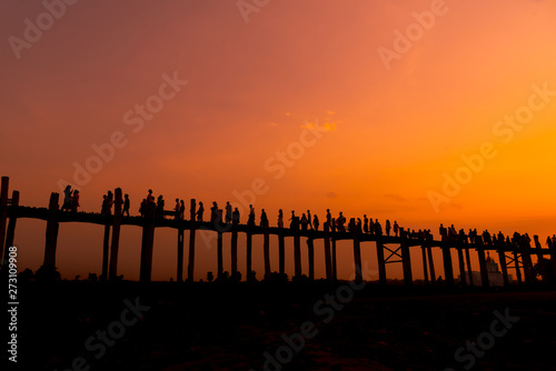 Silhouette the U Bein Bridge in Mandalay, Myanmar is a old biggest wooden bridge of the world and people come to sun set with sun sky background.
