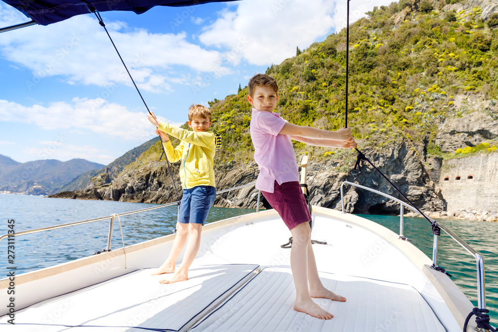 Two adorable school kid boys, best friends enjoying sailing boat trip. Family vacations on sea on sunny day. Children smiling. Brothers, schoolchilden, siblings, best friends having fun on yacht. Two adorable school kid boys, best friends enjoying sailing boat trip. Family vacations on sea on sunny day. Children smiling. Brothers, schoolchilden, siblings, best friends having fun on yacht.