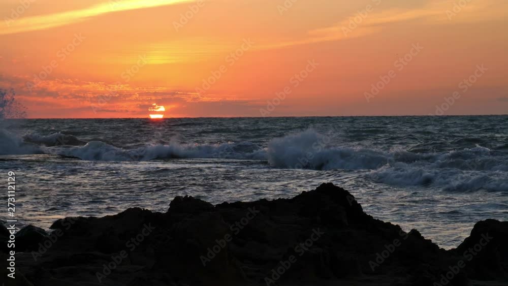 Romantic sunrise taken on the rocky coast of the Spanish town of Torrevieja in slow motion. The waves jump up in the sun and cause high spray. Romantic sunrise taken on the rocky coast of the Spanish town of Torrevieja in slow motion. The waves jump up in the sun and cause high spray.