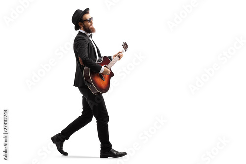 Male musician walking and playing an acoustic guitar photo