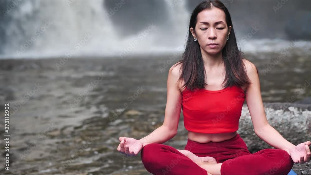 Asian woman practicing or doing yoga at the waterfall. Beautiful Landscape, Natural background, Thailand. Slow motion waterfalls. Asian woman practicing or doing yoga at the waterfall. Beautiful Landscape, Natural background, Thailand. Slow motion waterfalls.