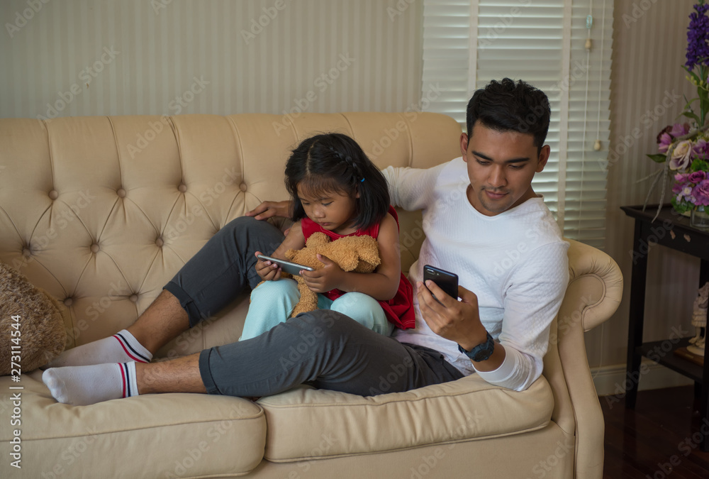 Father and daughter play phone on the sofa. Father and daughter play phone on the sofa.