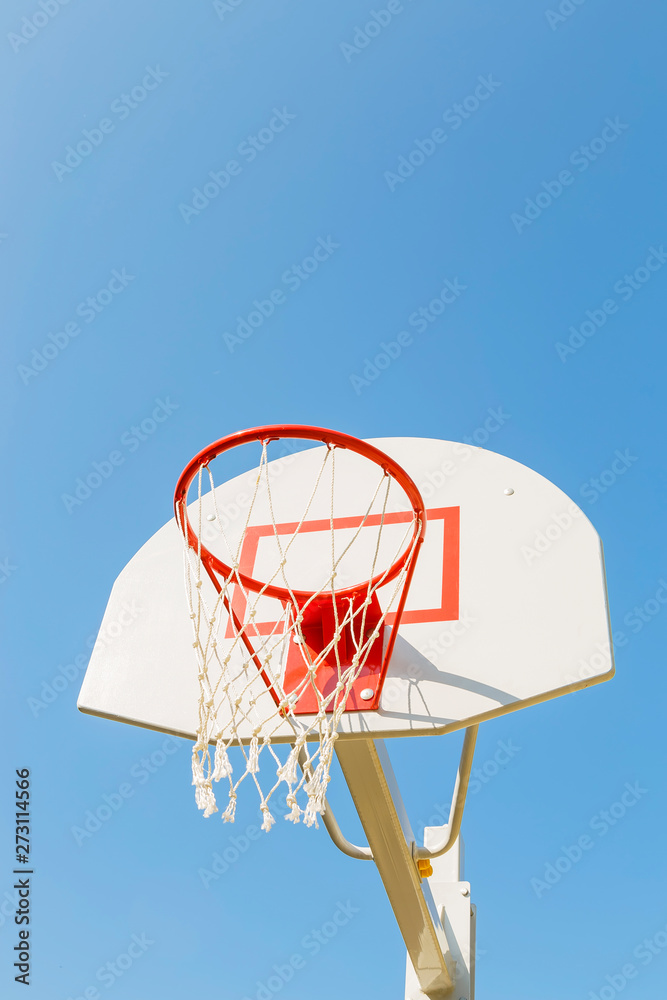 Game sports, competitions. Team sports, outdoor leisure, active recreation, entertainment. Basketball hoop with net on the backboard against the blue sky in the schoolyard outdoors