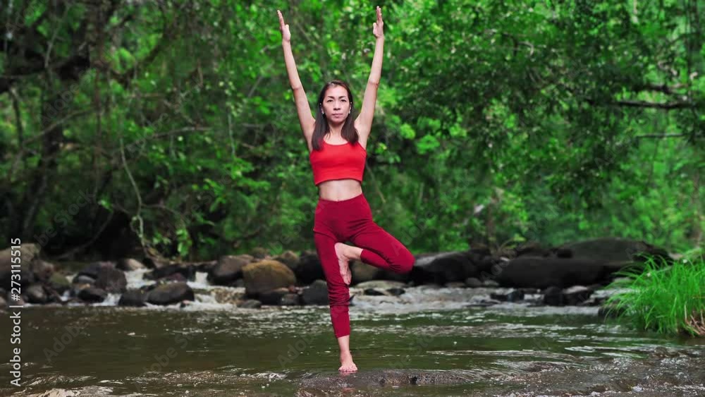 Asian woman practicing or doing yoga at the waterfall. Beautiful Landscape, Natural background, Thailand. Slow motion waterfalls. Asian woman practicing or doing yoga at the waterfall. Beautiful Landscape, Natural background, Thailand. Slow motion waterfalls.
