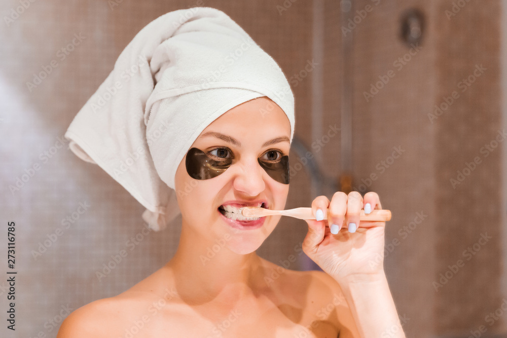 woman in patches brushing her teeth in the bathroom in the morning. Healty skincare and wellness concept woman in patches brushing her teeth in the bathroom in the morning. Healty skincare and wellness concept