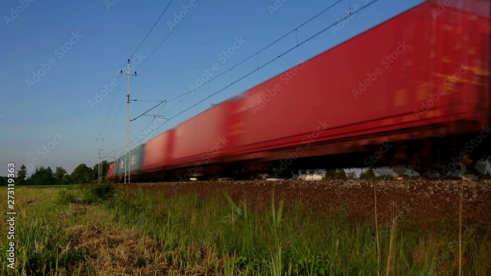 A fast freight train rushes around the railroad bend – loop footage. Wagons in endless and loopable motion. Cargo transport on rail.