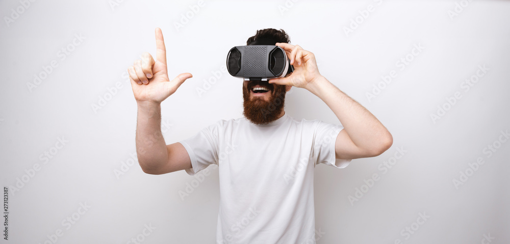 Bearded man looking through VR device touching something with a finger. Bearded man looking through VR device touching something with a finger.