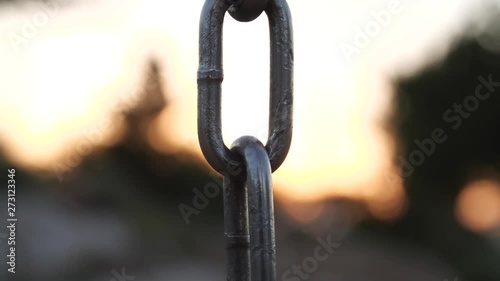 A strong, iron chain comes into focus against the backdrop of a diminishing sunset. photo