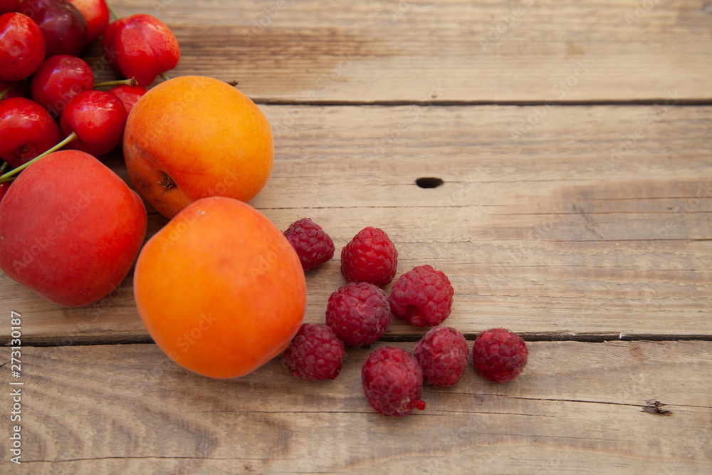 scattered berries from a plate of raspberry cherries apricots on a wooden table scattered berries from a plate of raspberry cherries apricots on a wooden table
