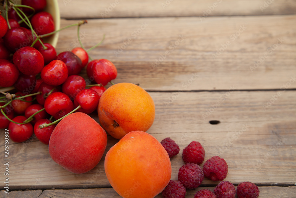 scattered berries from a plate of raspberry cherries apricots on a wooden table scattered berries from a plate of raspberry cherries apricots on a wooden table