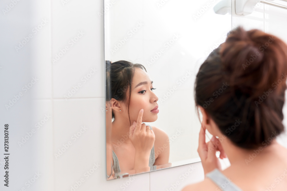 Skin care. Woman applying skin cream on her face in front of mirror Skin care. Woman applying skin cream on her face in front of mirror
