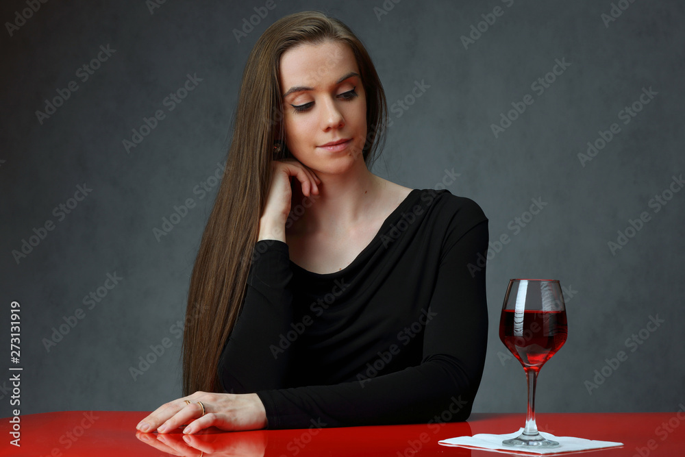 Cute girl at the red table with a glass of wine