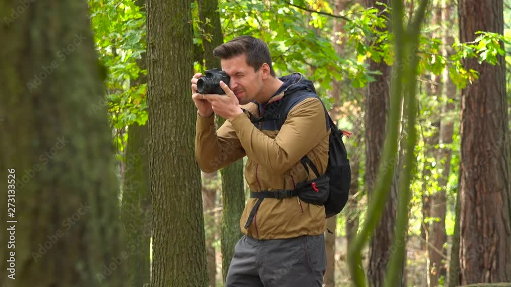 A hiker takes pictures with a camera in a forest A hiker takes pictures with a camera in a forest