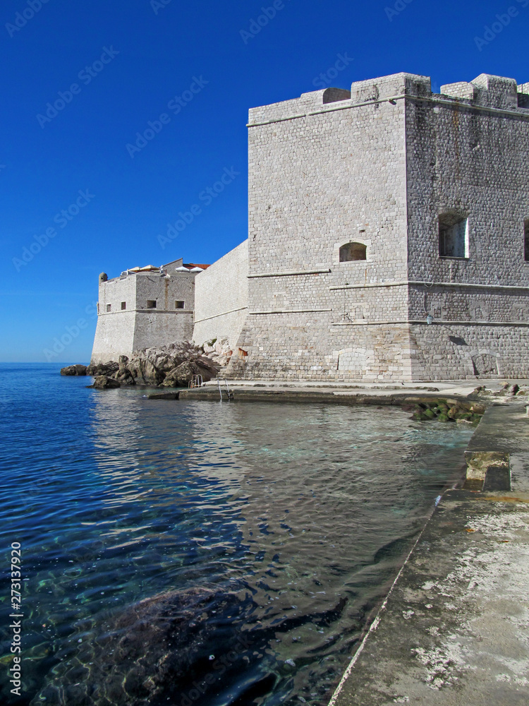 Old harbour of Dubrovnik, Croatia, Europe. Beautiful bright view with clear water, medieval fortress and blue sky on a summer sunny day.  