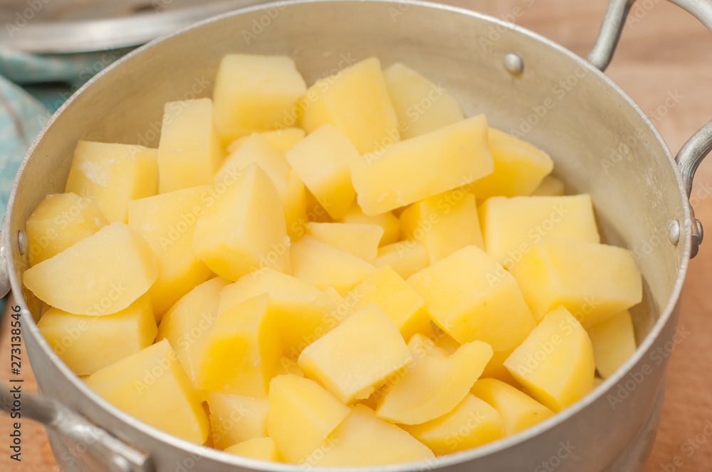 Boiled diced potatoes in an aluminum pan in the kitchen. Boiled diced potatoes in an aluminum pan in the kitchen.