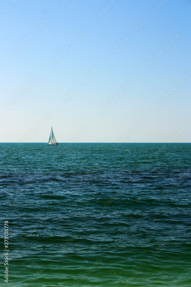Sailing boat on the horizon at sea