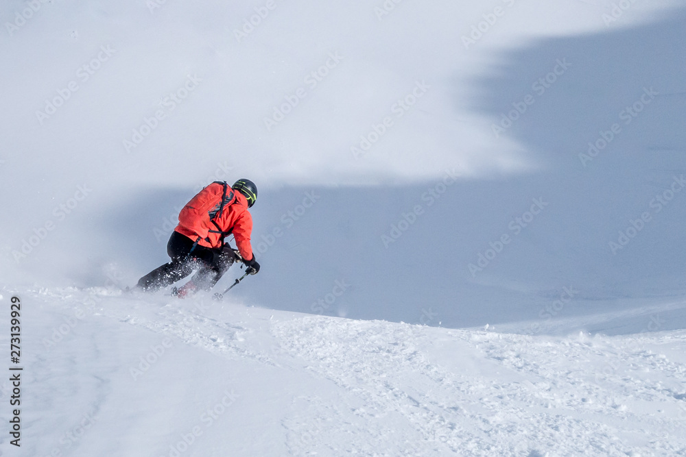 Single offpiste skier laying down first tracks on snow slope