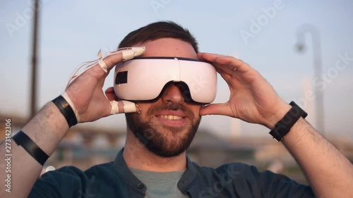 Caucasian desability man in wheelchair using virtual reality headset at sunny day outdoors. Technology concept. photo