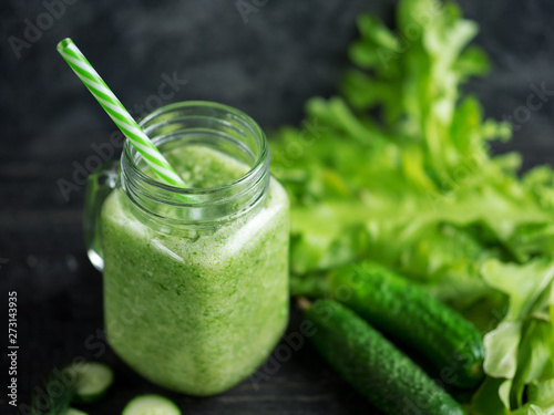 Close-up of green smoothie in a glass jar with ingredients on a dark wooden table