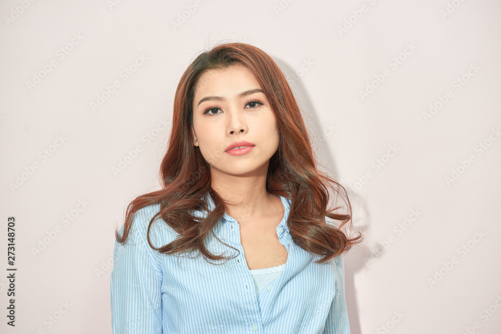 Beautiful lady in trendy blue blouse looking at camera with confident face expression while standing on light pink background Beautiful lady in trendy blue blouse looking at camera with confident face expression while standing on light pink background