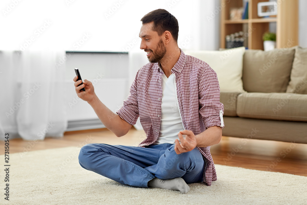 Obraz premium technology, yoga and relaxation concept - man with smartphone meditating at home
