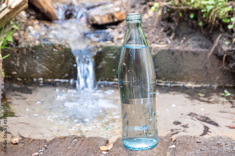 Glass bottle on the background of pure spring water. Natural water.