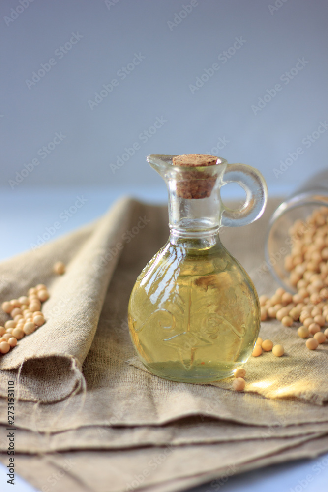 Natural soybean oil in glass bottle with soy beans near it.