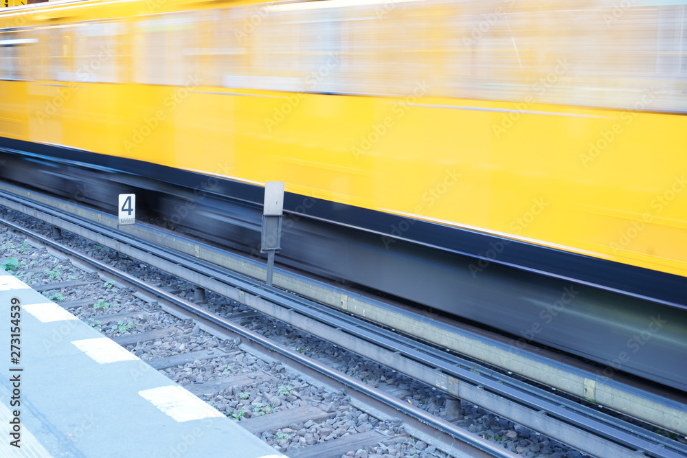 Fototapeta premium Fast moving yellow train in Berlin Germany - motion exposure
