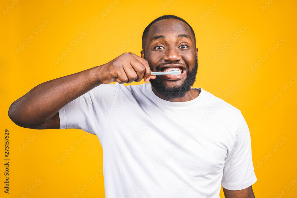 Man with tooth brush. Image of young shirtless African man holding a toothbrush with toothpaste and smiling while standing against yellow background. Man with tooth brush. Image of young shirtless African man holding a toothbrush with toothpaste and smiling while standing against yellow background.
