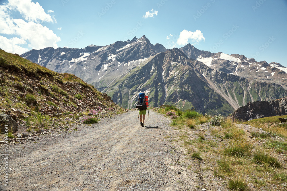 climber on trail in the mountains. a man with a backpack in a hike