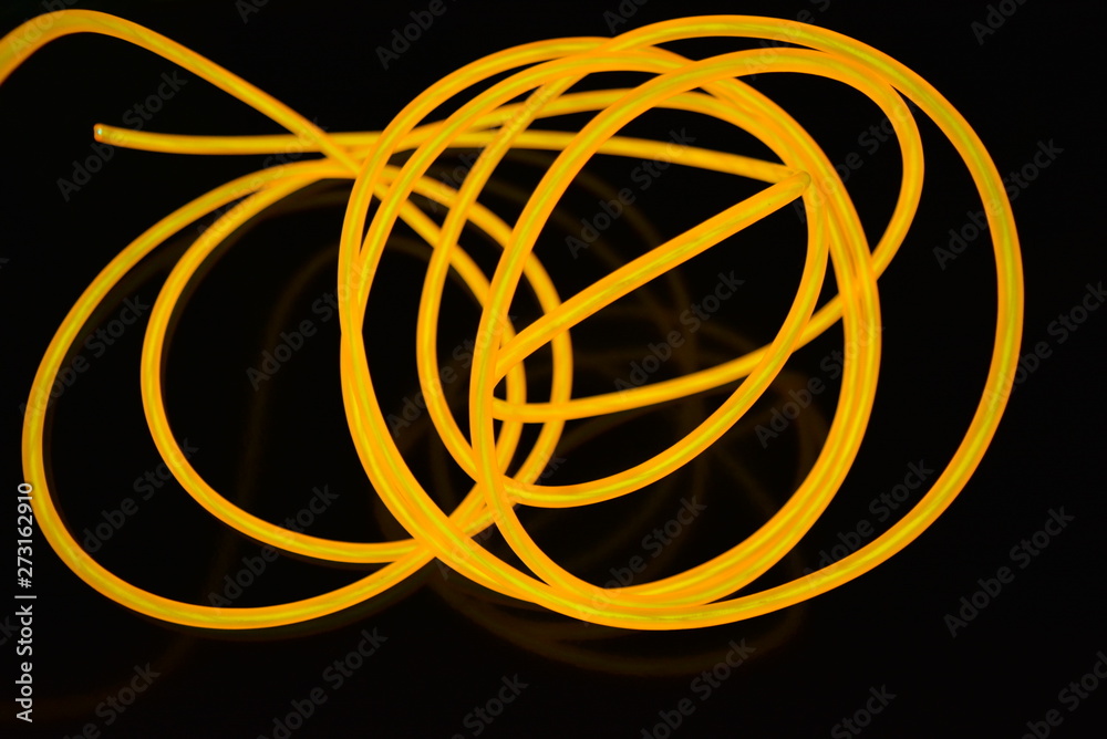 The original yellow lighting of thick electoluminescent wires and lines. Graphic abstract light background with interesting combination of shapes and textures. The original yellow lighting of thick electoluminescent wires and lines. Graphic abstract light background with interesting combination of shapes and textures.