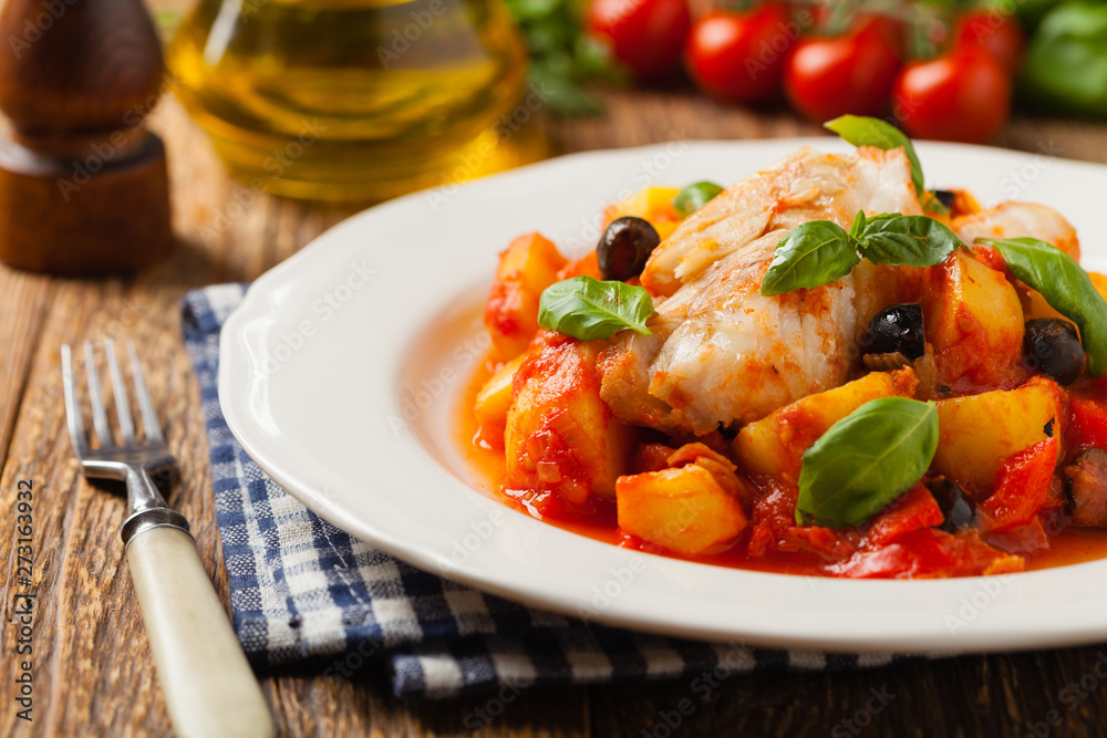Traditionally prepared cod in Spanish. Served in tomato sauce with boiled potatoes, olivki and basil. Front view. Traditionally prepared cod in Spanish. Served in tomato sauce with boiled potatoes, olivki and basil. Front view.