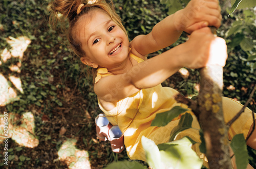 Foto Outdoors image of adorable cute blond little girl playing and smiling broadly at nature background