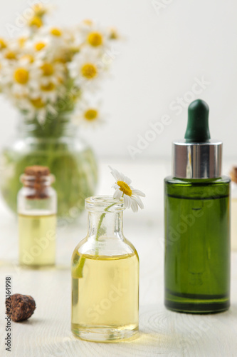 Chamomile. Medicinal little flowers of chamomile with aroma oils on a white wooden table. close-up