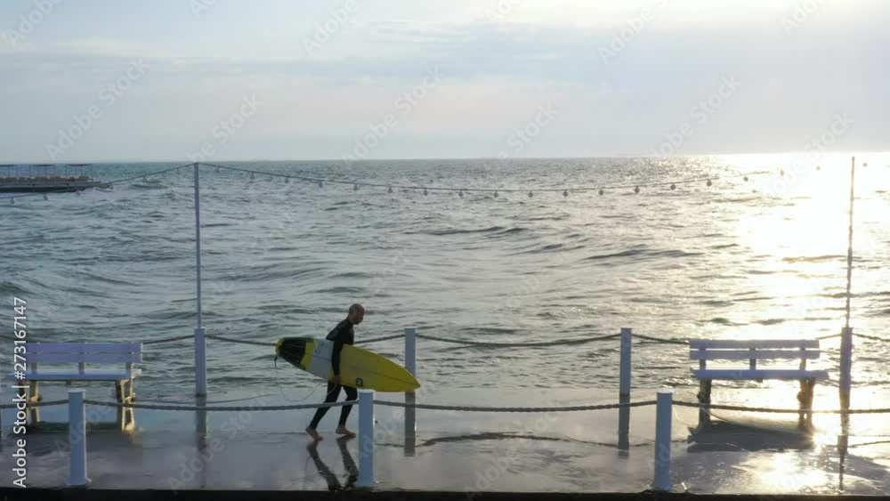 surfer with surfboard walking on pier surfer with surfboard walking on pier