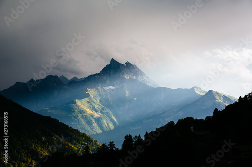 Shafts of sunlight through clouds illuminate mountain