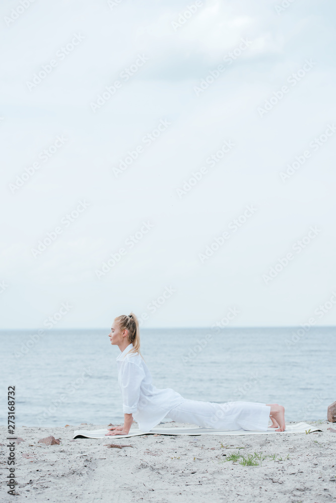 side view of young woman practicing yoga near river