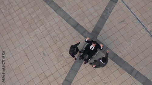 AERIAL. Arms of three business people stacked together in unity and teamwork. Hands of businessman team getting together in the center of a circle and then raised up. Top view. photo