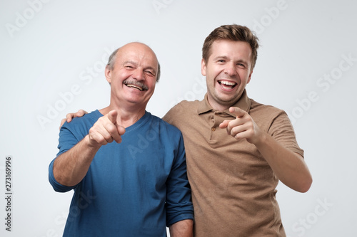 Father and son pointing at camera with index finge