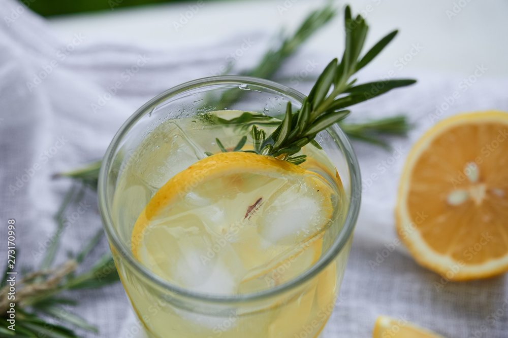 a glass of lemonade with a slice of lemon and rosemary on a white napkin top view a glass of lemonade with a slice of lemon and rosemary on a white napkin top view