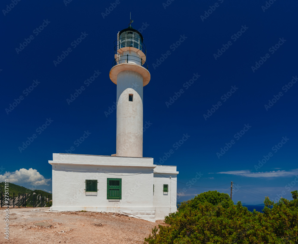Lighthouse building on rocky coast with deep blue sky