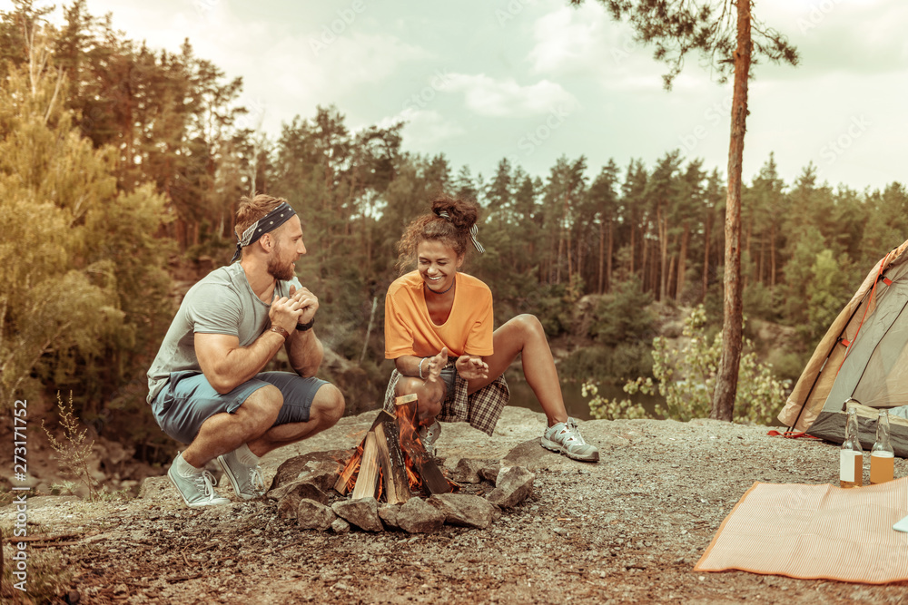 Positive joyful couple sitting near the fire Positive joyful couple sitting near the fire
