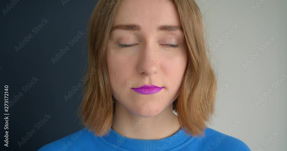 Closeup portrait of young short haired female with purple lipstick looking at camera isolated background Closeup portrait of young short haired female with purple lipstick looking at camera isolated background