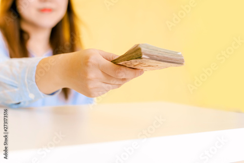 home business and job success concept from soft focus beauty woman in happiness feeling show and give lot of banknote for payment with yellow pastel background