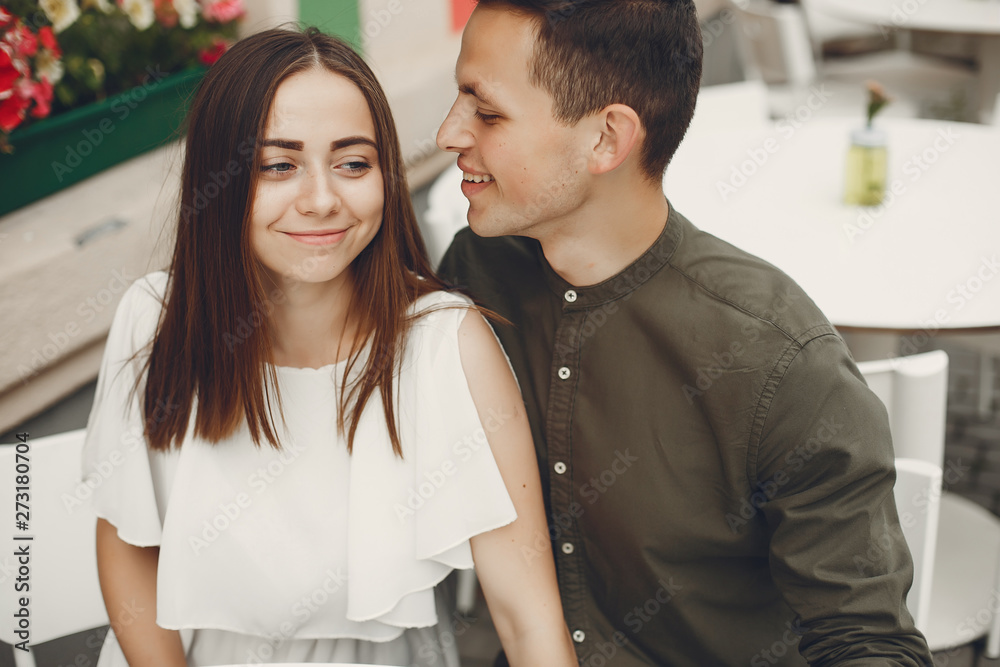 Cute couple in a city. Lady in a white dress. Pair sitting on a cafe Cute couple in a city. Lady in a white dress. Pair sitting on a cafe