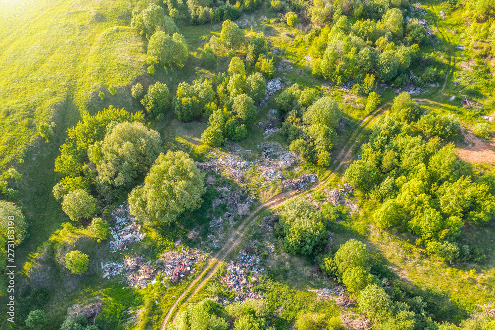 Large landfill of garbage, household waste, plastics and other things among the green forest along the meadows and the road. Aerial view from above drone. Large landfill of garbage, household waste, plastics and other things among the green forest along the meadows and the road. Aerial view from above drone.